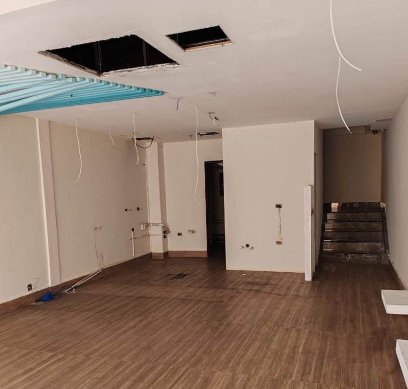 Large empty interior space with tiled accent wall utility piping and unfinished ceiling at Plaza San Francisco