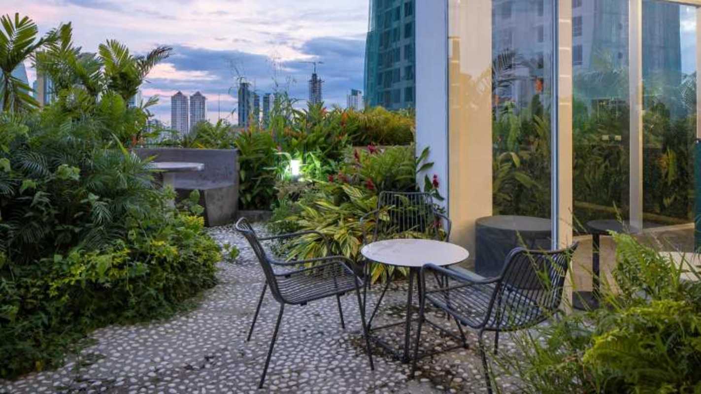 Rooftop garden with lush landscaping, seating area, and skyline views at PH El Cangrejo Panama City