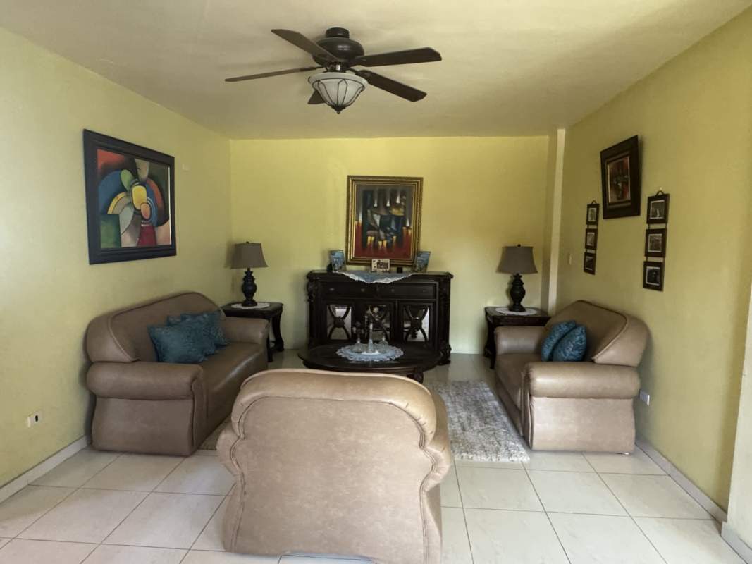 Living room with beige sofas, ceiling fan, tile floors, bright windows in Villas de Cerro Lindo Panama