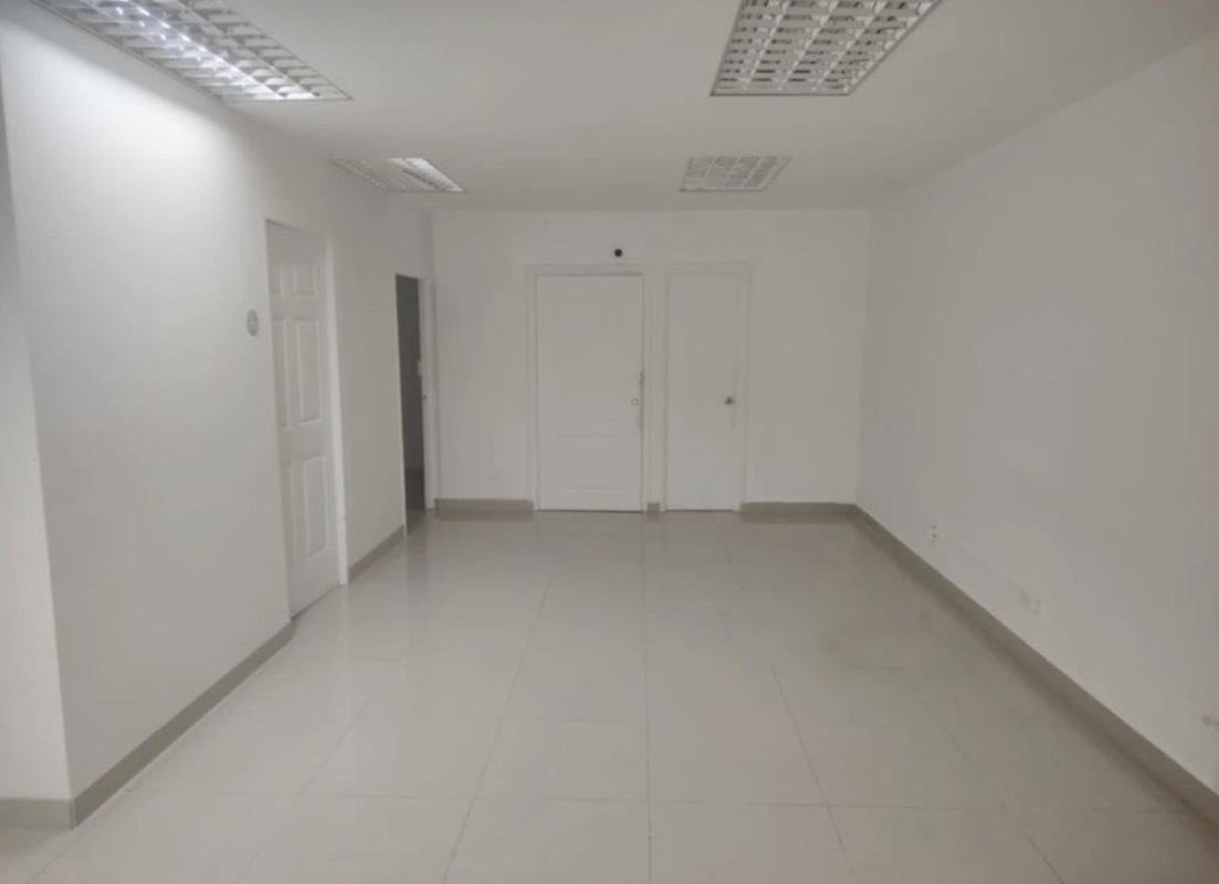 Bright empty office room with tiled flooring, white walls, fluorescent lighting and multiple doors inside El Dorado Mall
