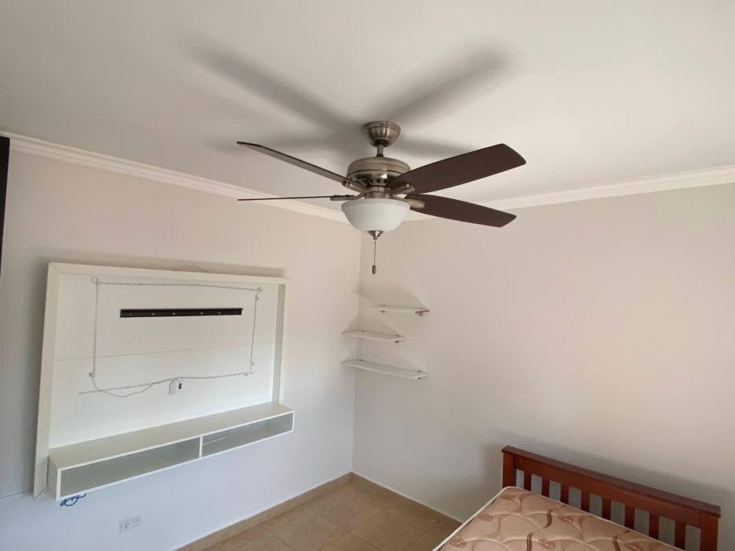 Bedroom with ceiling fan, built-in TV panel, closet, and corner shelves at PH Cosmopolitan Transístmica Panama