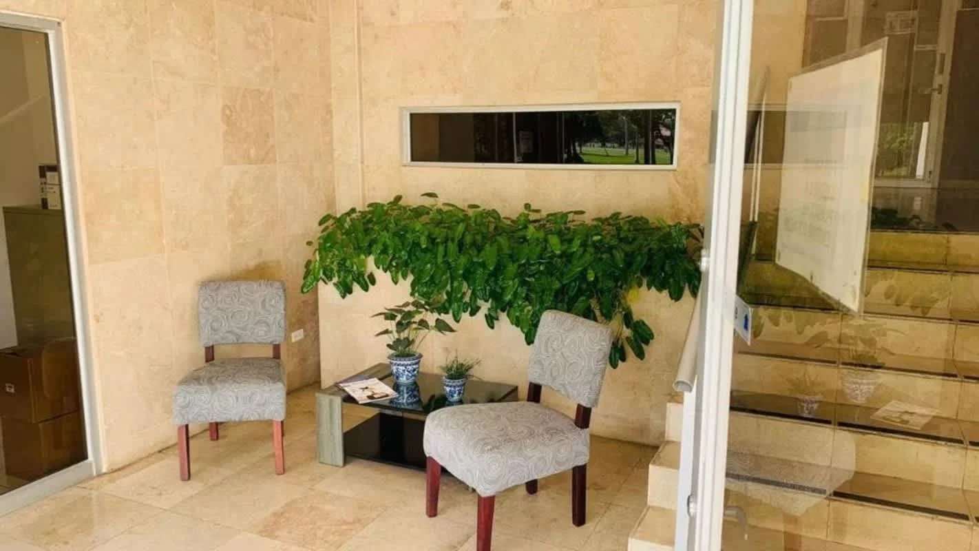 Lobby with marble walls, seating area, glass doors and plants at PH Canal View Clayton Panama City