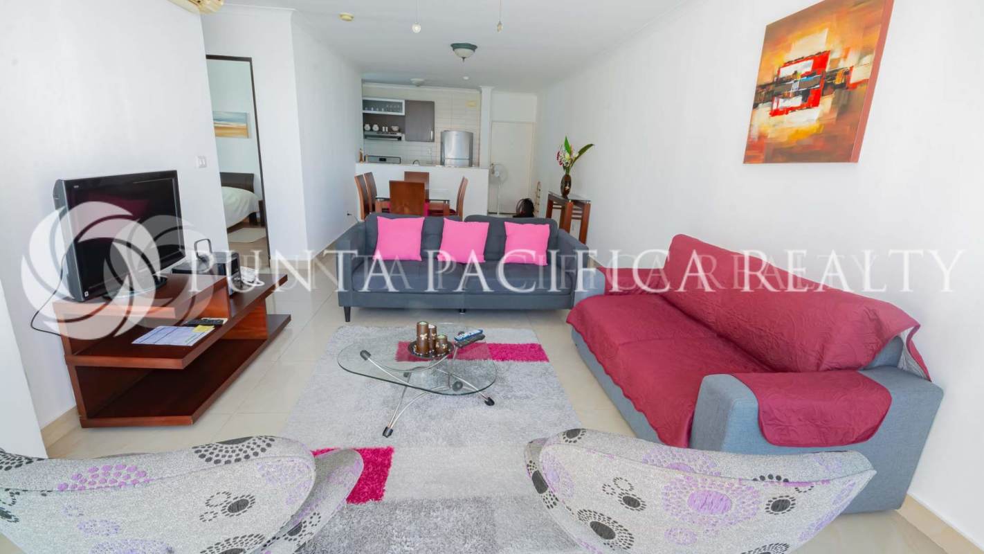 Open-plan living room with sofas, large windows, balcony access in Punta Pacífica apartment