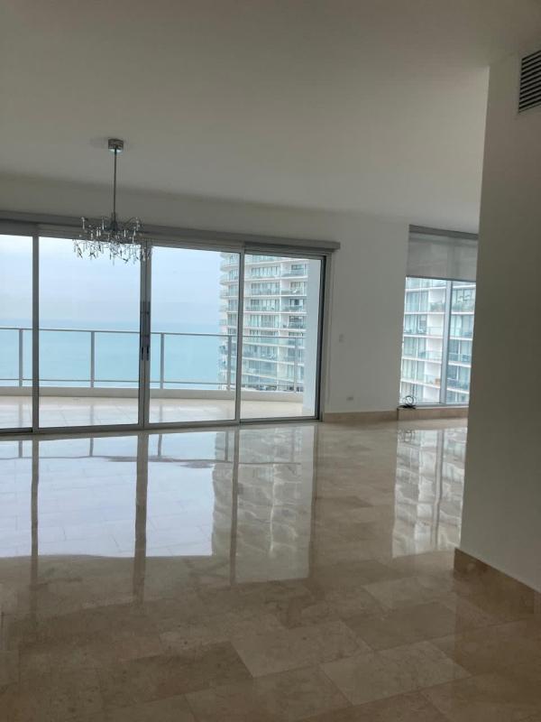 Luxury unfurnished living area with marble floors and floor-to-ceiling glass doors opening to balcony ocean view PH Pacific Village Punta Pacifica