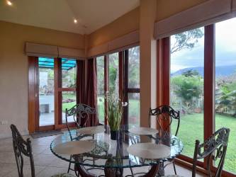 Bright dining area with glass table chairs and panoramic garden views in Boquete