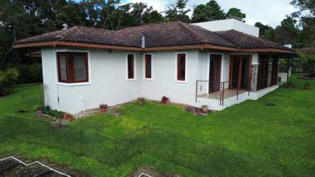 Bedroom with large window overlooking garden, wood closet, ceiling fan in Boquete house