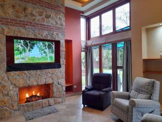 Cozy living room with stone fireplace, mounted TV, big picture windows Boquete Panama