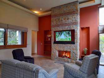 Stylish living room with stone fireplace, TV, natural light in Santa Lucia Boquete house
