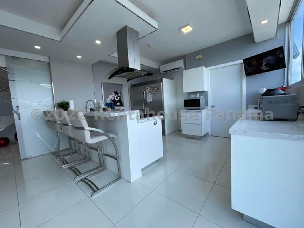 Modern kitchen with large island, white cabinetry, stainless appliances, floor-to-ceiling windows, ocean view Coco del Mar Panama