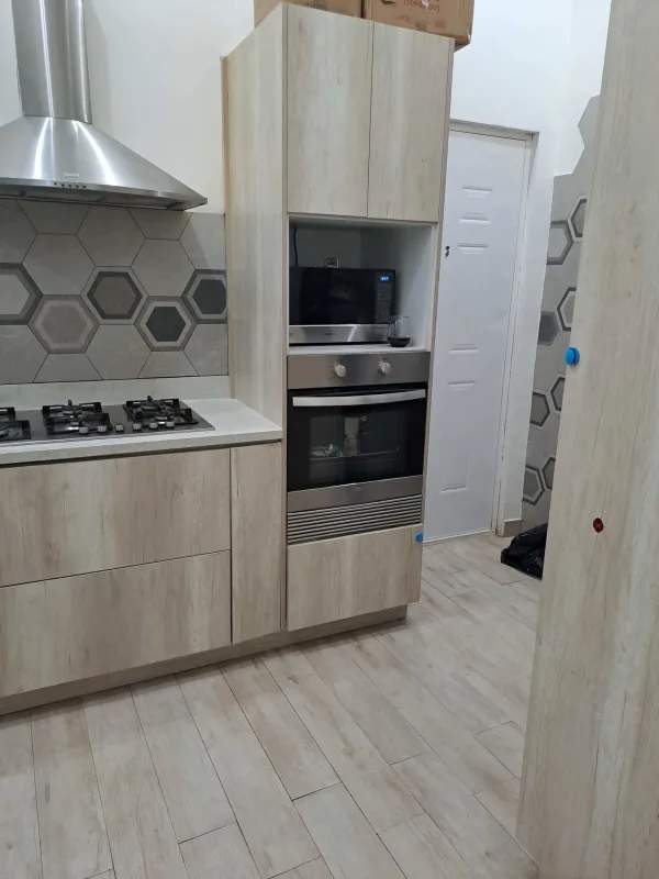 Light wood cabinetry, stainless hood, hexagonal tile in modern kitchen villa de las fuentes