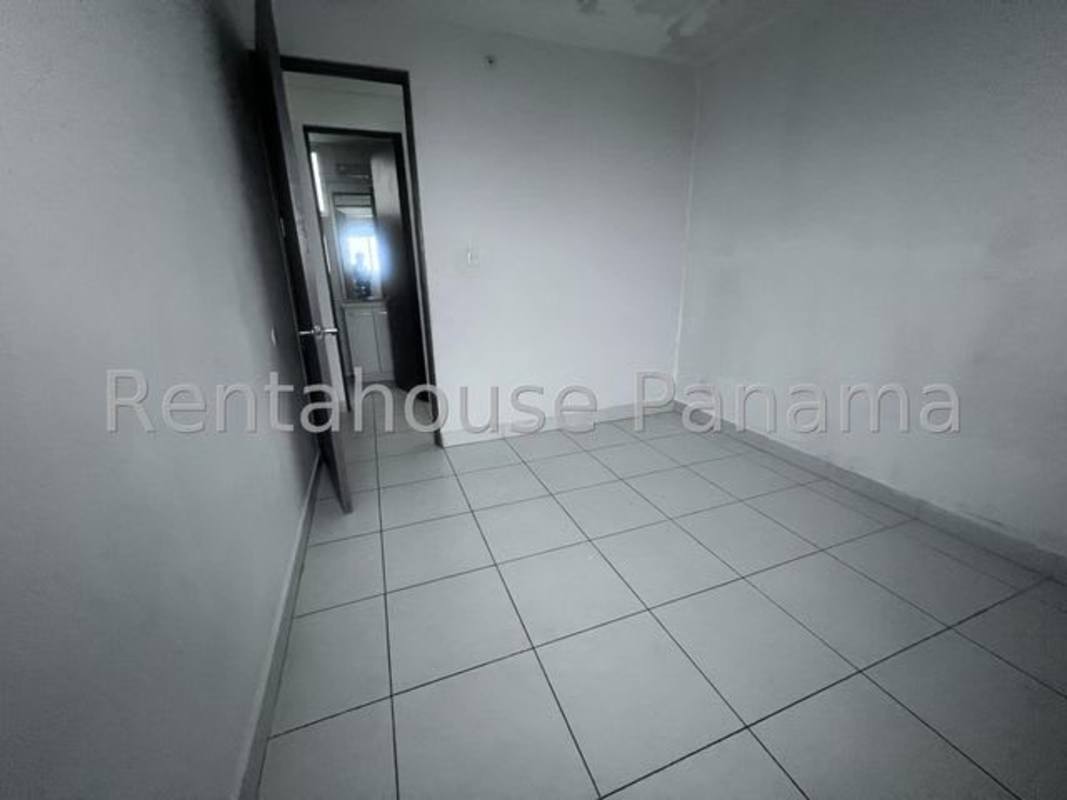 Modern minimalist kitchen with white cabinets, large window and natural light in Panama apartment