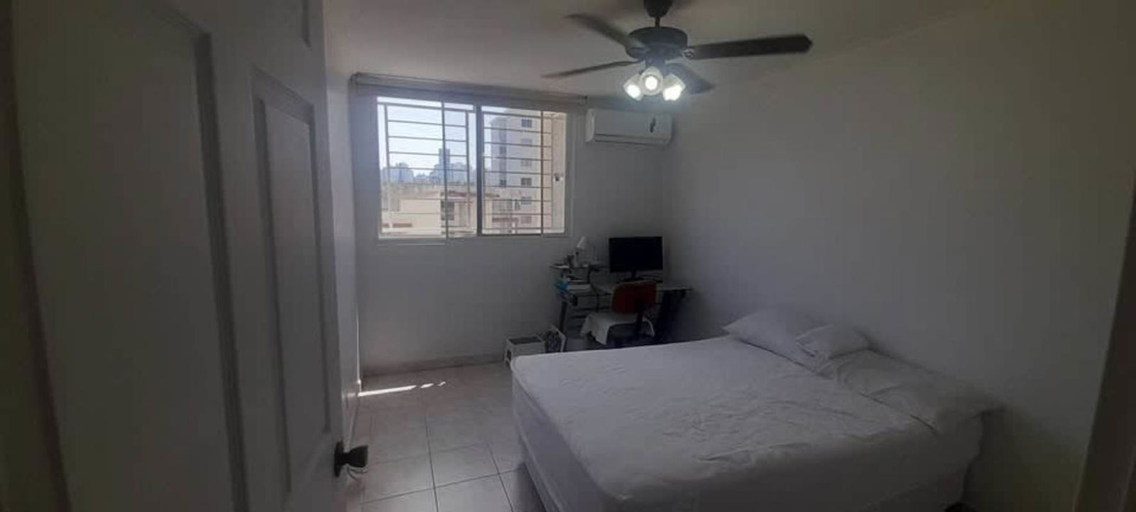 Bright furnished bedroom with window, closet, AC and ceiling fan in Panama City apartment