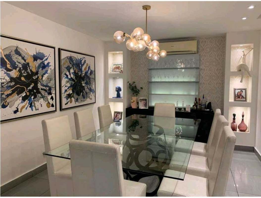 Large dining area with glass table, chandelier, and bar in PH Mystic Point Panama