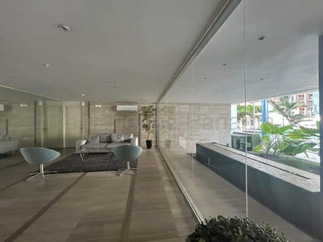 Modern lobby with glass walls, lounge chairs and green plants PH Vista Balboa Panama
