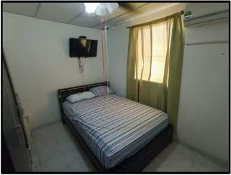Small bedroom with AC unit, striped bedding, window curtain, tiled flooring in affordable house Panama