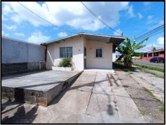 Simple bright living room with tiled floors, shelving, armchairs, large window in La Chorrera residence