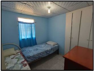 Bedroom with two single beds, white wardrobe, wooden desk and blue curtains in Panama home