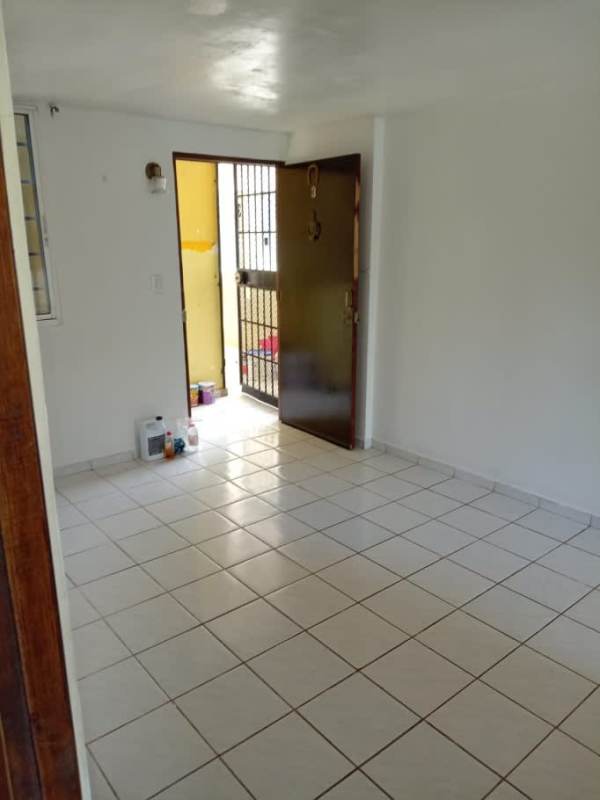 Living area with white tile floor, orange accent wall, wood doors in apartment La Chorrera Panama