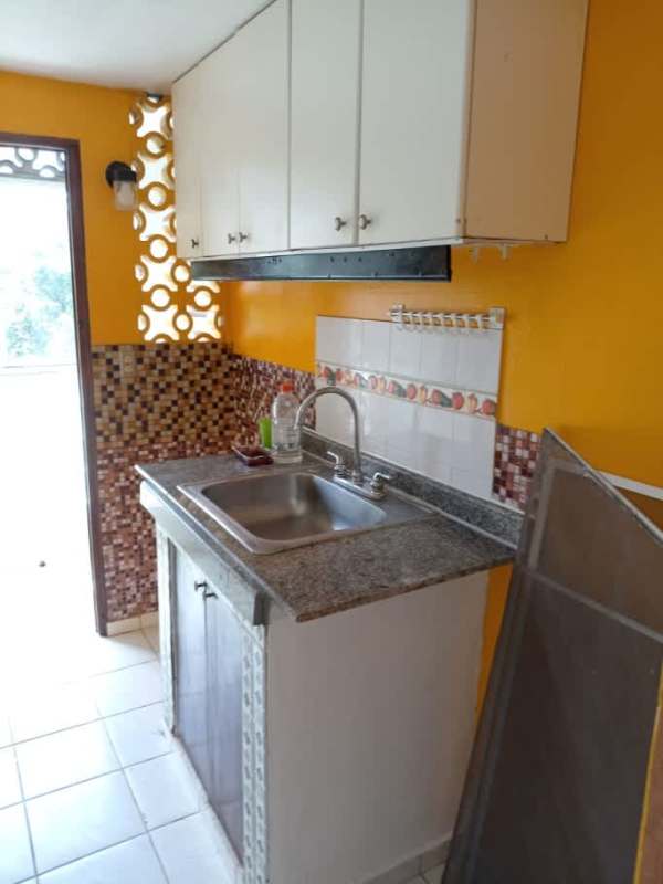 Compact apartment kitchen with yellow walls, mosaic backsplash, white cabinets La Chorrera