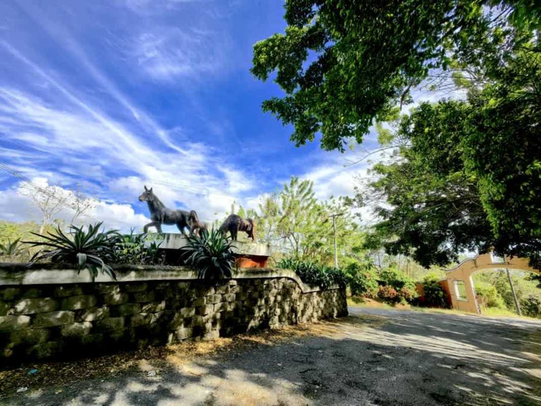 Rustic stone-clad gated entrance with sculptures at Hacienda Country Club Panama