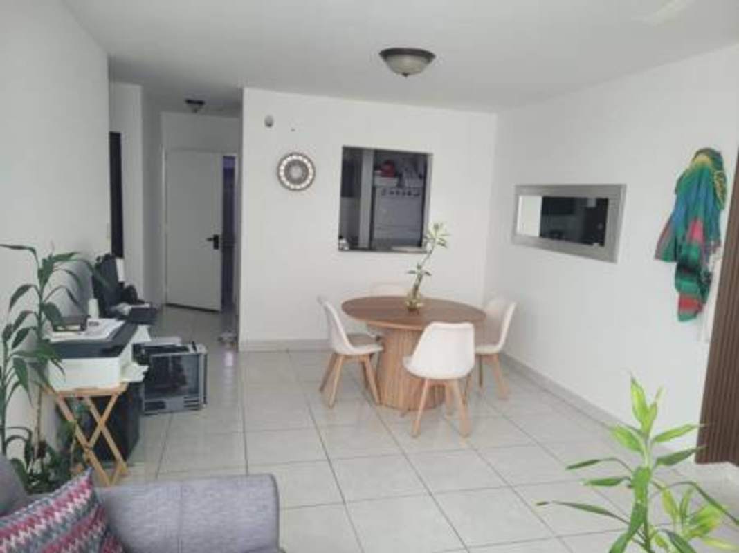 Dining with round table and gray sofa, service window to kitchen, bright living in Vivendi 300 Panama City