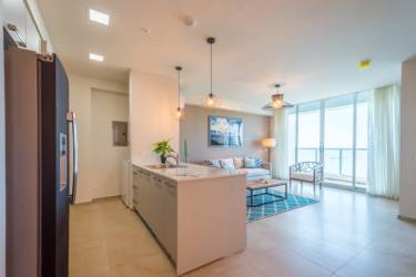 Modern open concept living room and kitchen with ocean view windows at Royal Palm Playa Gorgona Panama