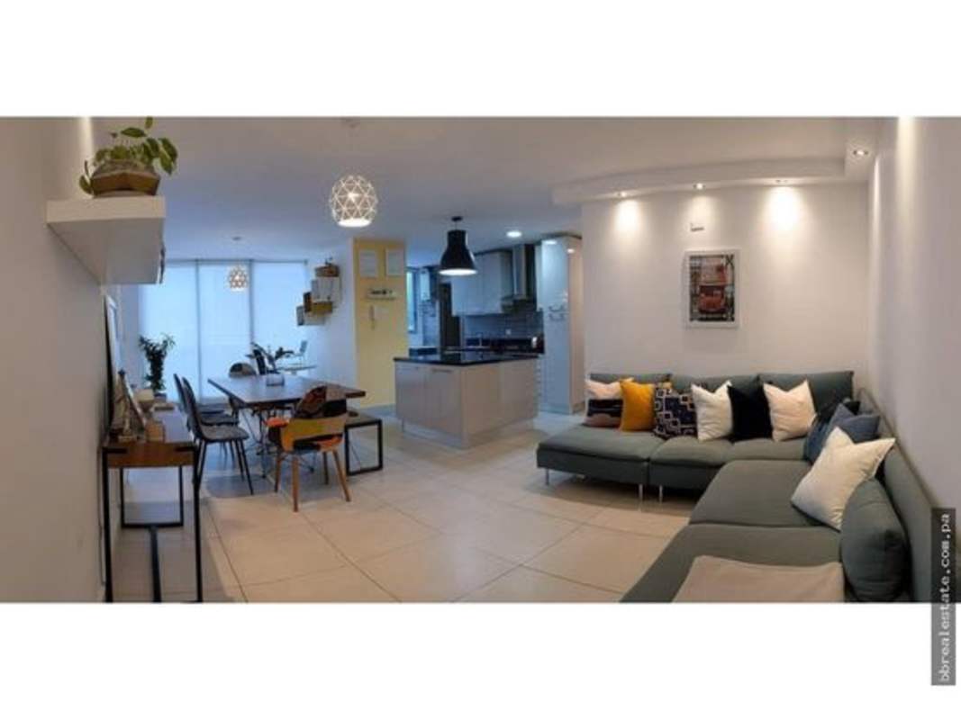 Open-plan living area with teal sofa, dining, kitchen and pendant lighting in PH Park City Panama