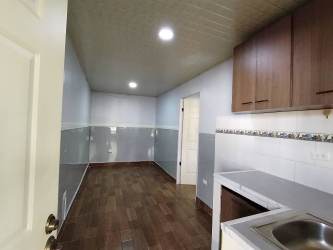 Small modern kitchen with wood-look flooring, white cabinets in Villa Liriola Cativa Colón apartment for rent