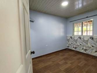 Bedroom with wood-style flooring, marble accent wall, natural light in Villa Liriola Cativa Colón