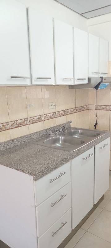 Compact kitchen with granite counters, double sink, upper cabinetry in Las Acacias apartment Panama