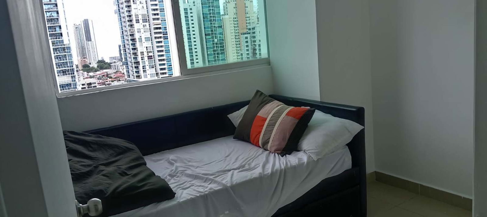 Bright bedroom with large window offering skyline views, minimalist design in PH Red Point Panama City