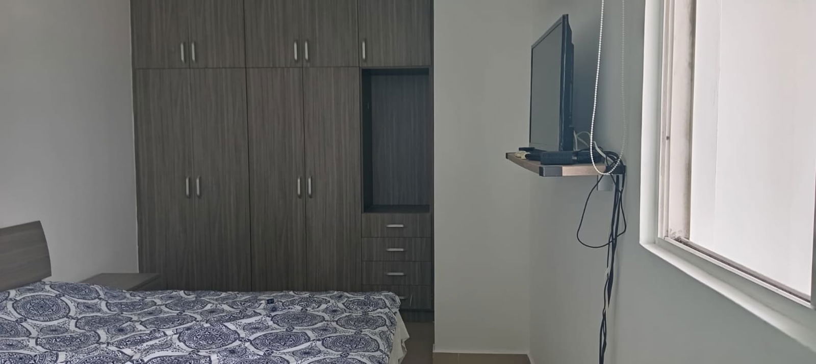 Bedroom with fitted wardrobe, wall-mounted TV setup, large window in PH Red Point San Francisco Panama