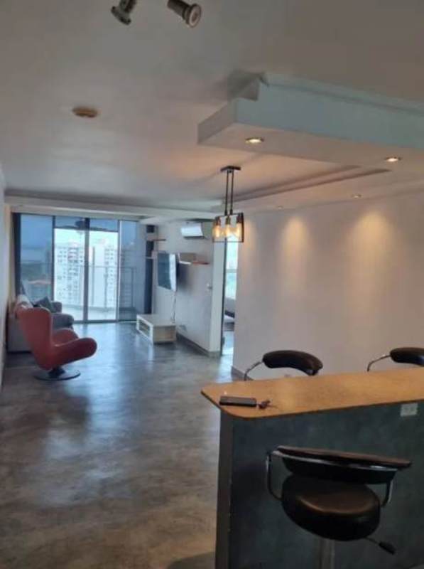 Open-plan living with kitchen bar, red lounge chair, and balcony city view at PH Park Lane Tower Panama