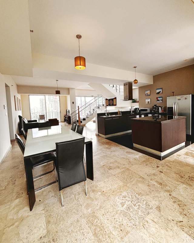 Spacious open-plan kitchen with island, modern appliances, dining area with city view windows at PH Denovo Obarrio