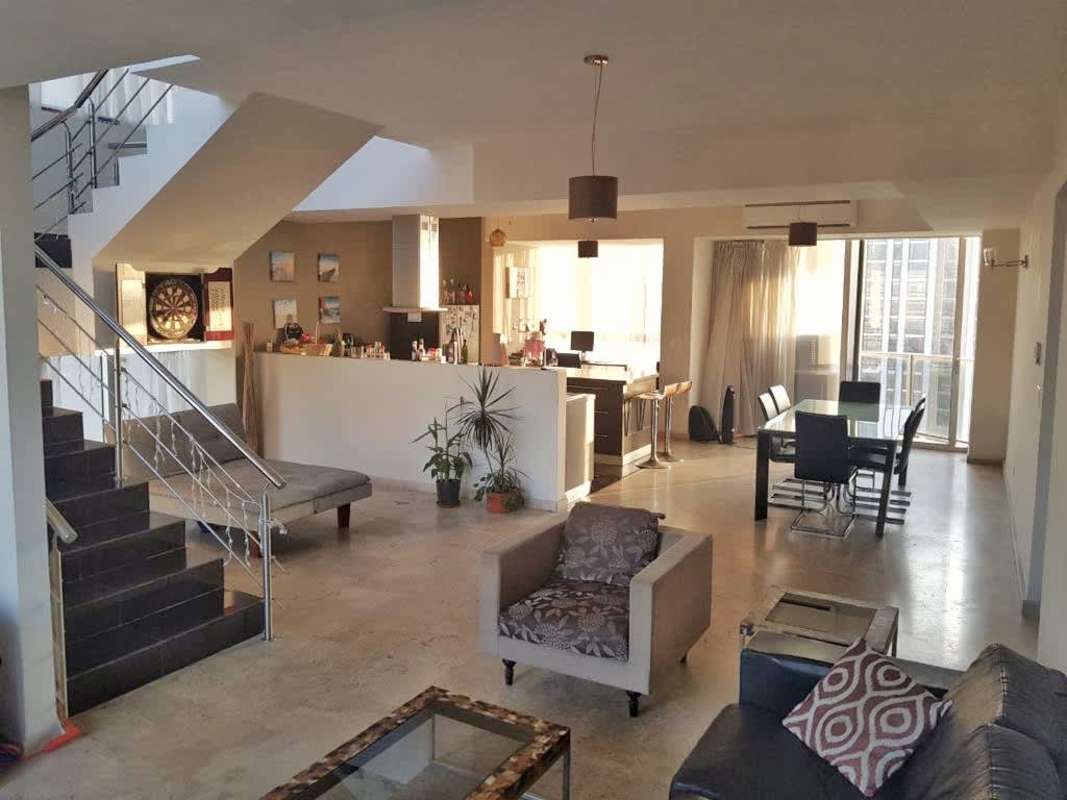 Spacious living dining open area with large windows, staircase, modern furnishings in PH Denovo Obarrio Panama