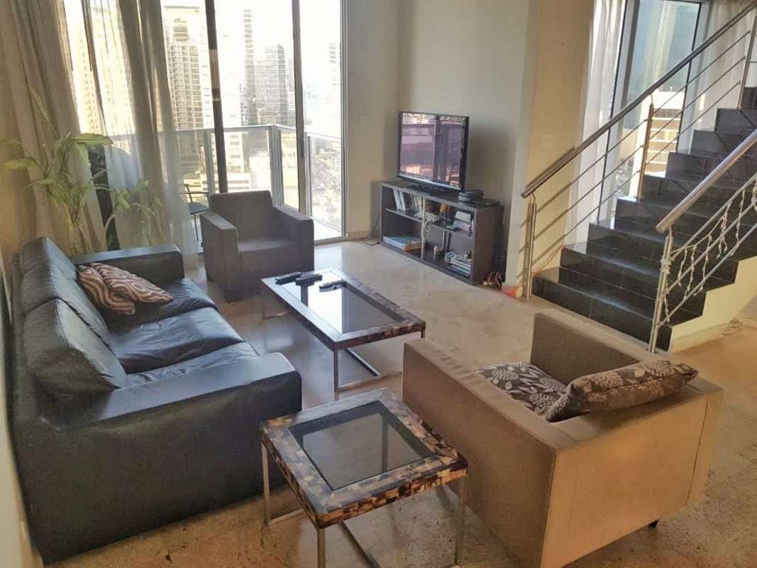 Modern living room with large windows overlooking city skyline, leather sofa, contemporary decor in PH Denovo Panama