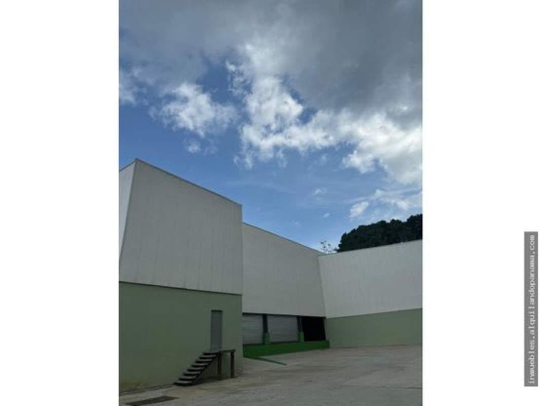 Exterior green and white panel industrial warehouse with stairs and large doors Panama City