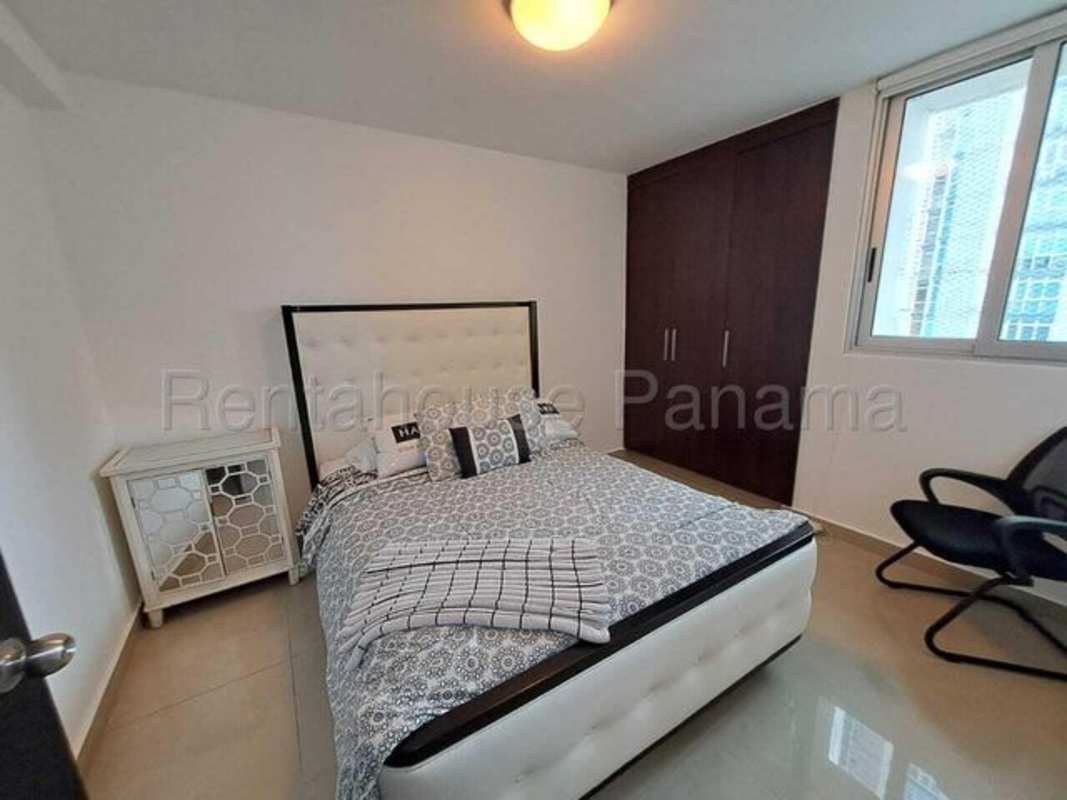 Bedroom with large built-in wardrobe, upholstered bed, modern decor, bright window in Bella Vista Panama City