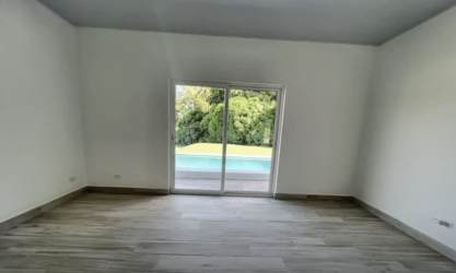 Spacious living room with sliding glass doors overlooking private garden and swimming pool in Villas del María Bejuco