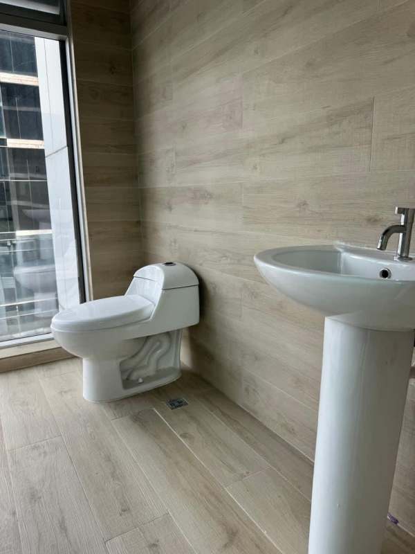 Office bathroom with pedestal sink, wood-look tiles, floor-to-ceiling window in PH Atrium Tower Panama