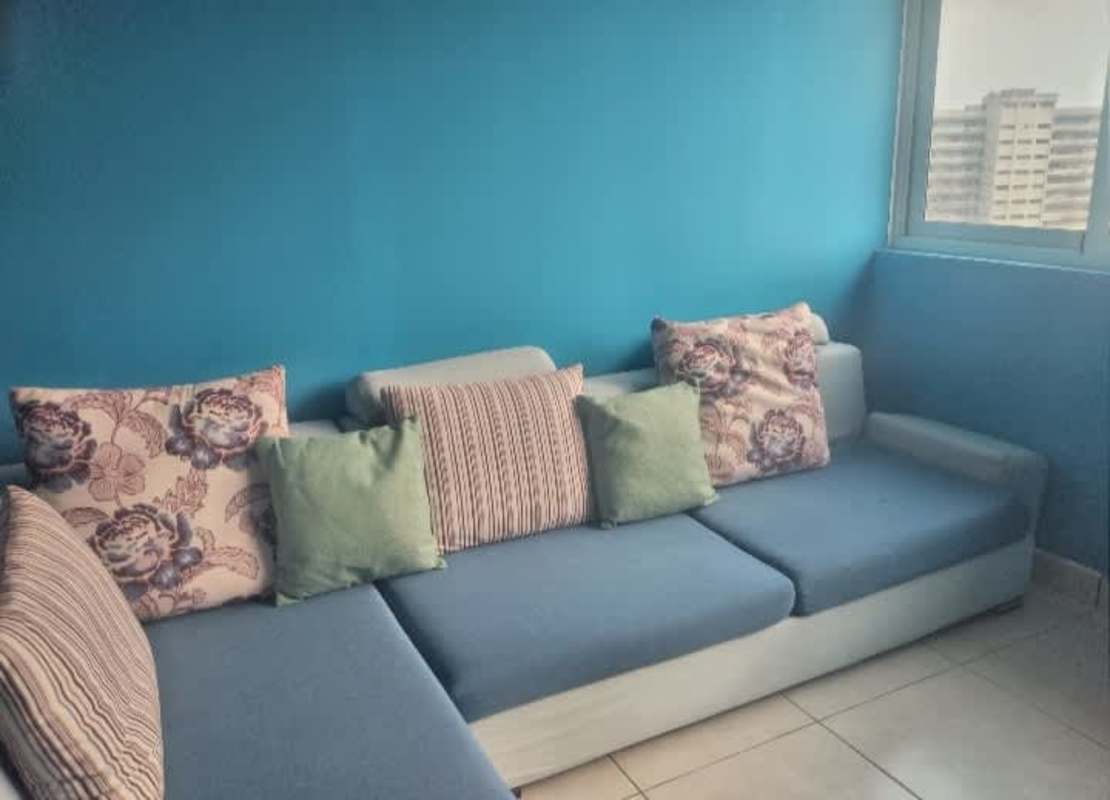 Bright living room with blue couch, city view window PH Bay View Panama City