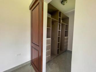 Walk-in closet with built-in shelves and warm wood door in modern Boquete house