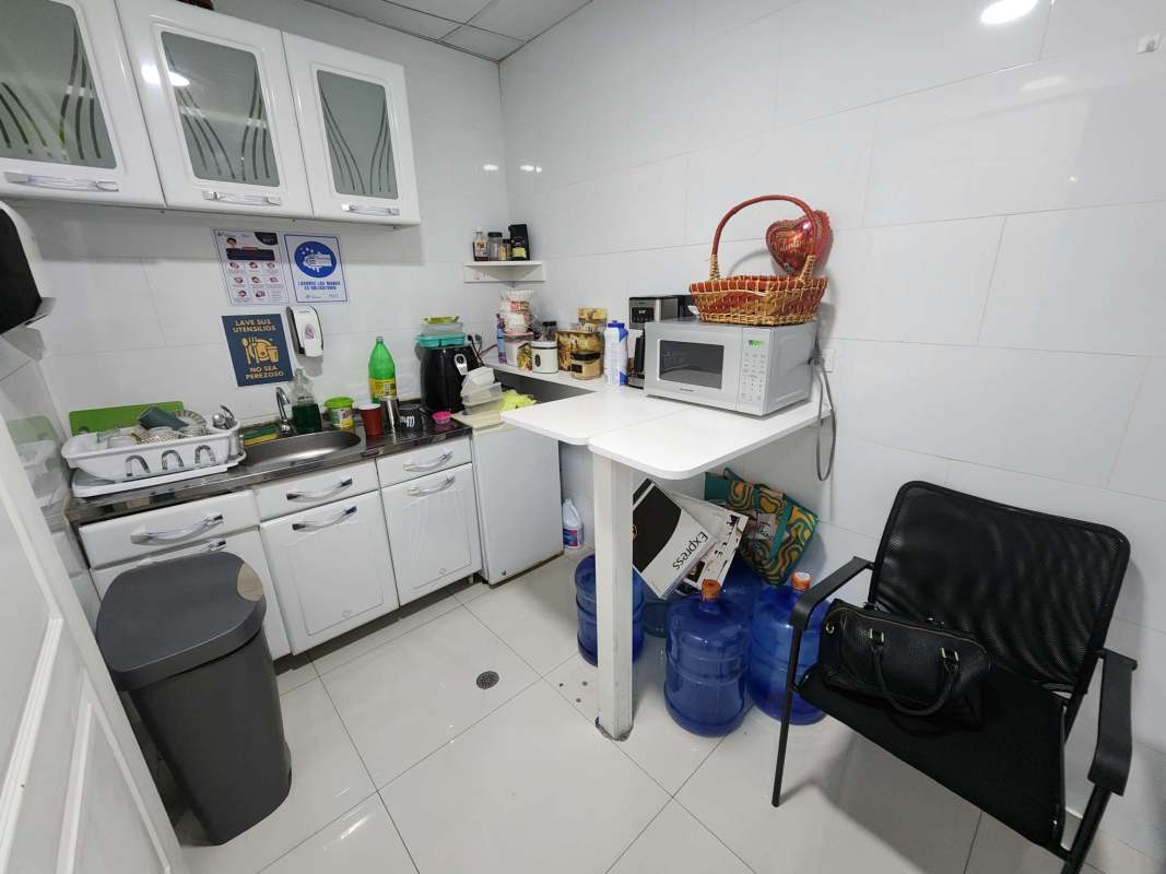 Compact kitchenette in Oceania Business Plaza office space with white cabinets, microwave, and sink