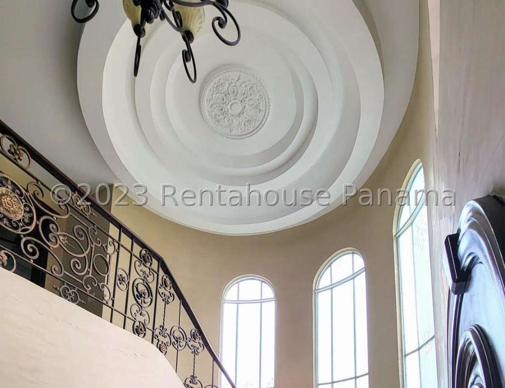 Curved ornate staircase with iron railing and arched windows luxury house in Panama