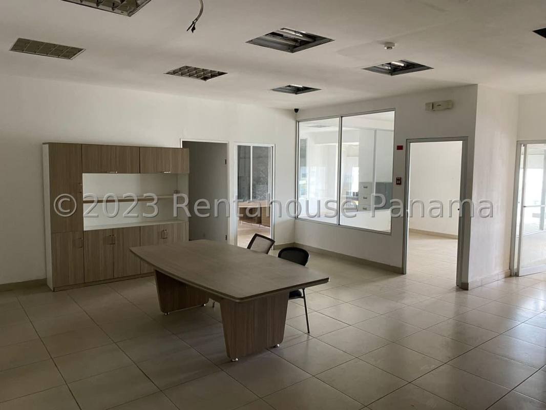 Empty office tiled floor glass partitions light wood furniture Pacora Panama