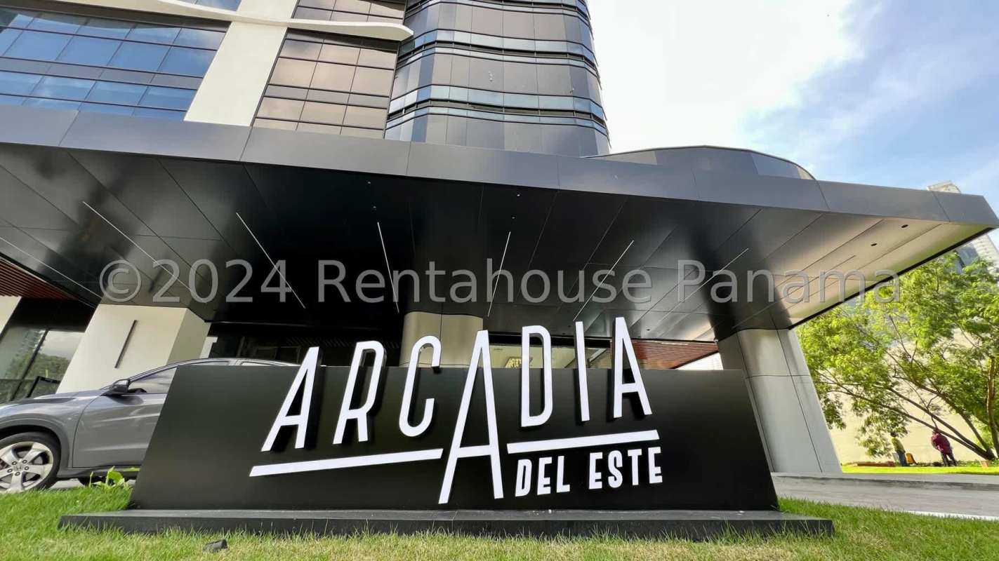 Modern glass facade of Arcadia Tower in Costa del Este, Panama with driveway and palm landscaping