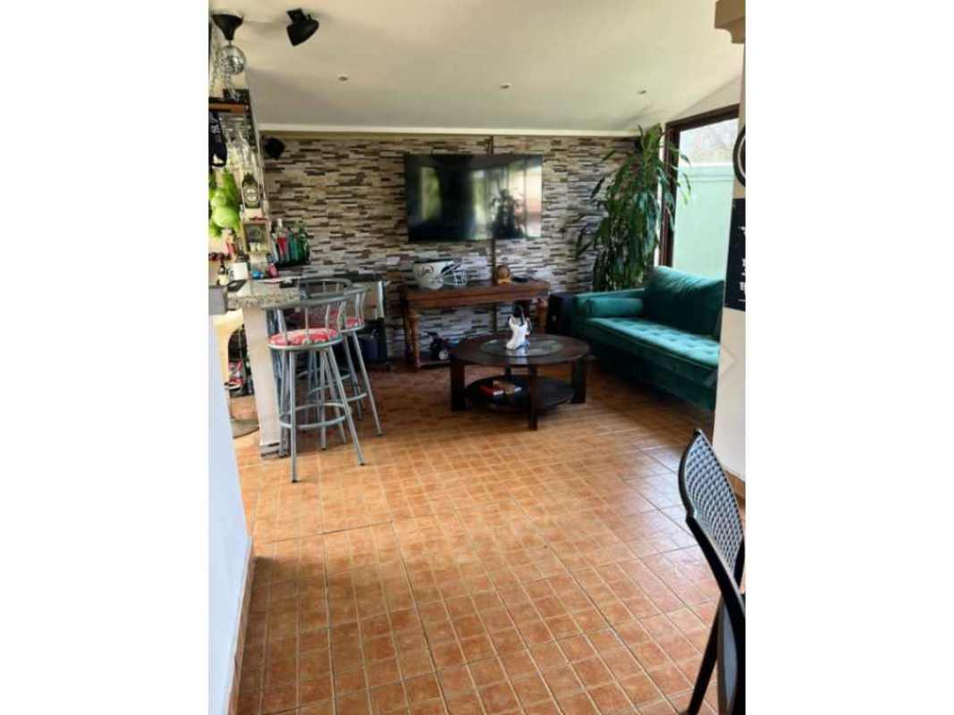 Living room with green velvet sofa, stone accent wall, and open entertainment area in Condado del Rey house Panama