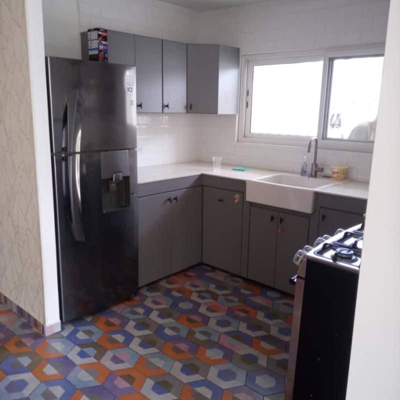 Kitchen with gray cabinets, geometric tile floor, refrigerator, farmhouse sink PH Sandra La Cresta Panama