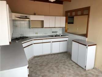 Traditional L-shaped kitchen with white cabinets tile backsplash gas stove in El Dorado house Panama