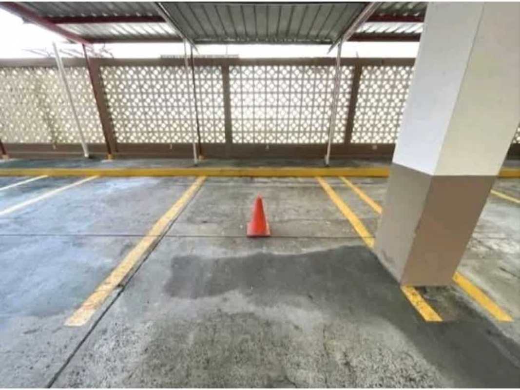 Covered parking area with privacy wall, yellow lines and concrete floor at PH Hilton Park Panama City